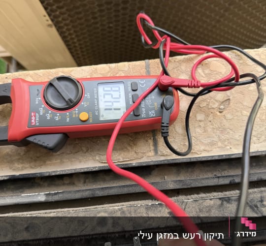 מד מתח מחובר למכשיר חשמלי עם חוטים אדומים